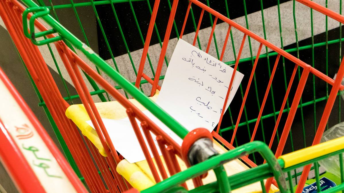 Smiling woman holding headphones while standing next to laptop displaying refund confirmation email.